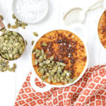 An overhead shot of pumpkin creme brulee topped with pumpkin seeds on a fall napkin.