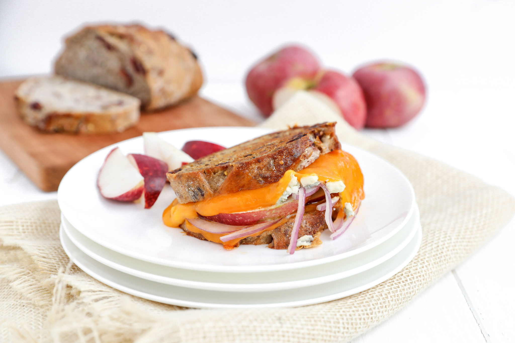 Grilled Apple Cheddar and Blue Cheese via JennyShea Rawn Grilled cheese and apple sandwich on a plate with apple slices