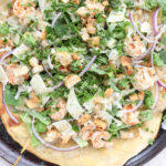 Grilled shrimp Caesar salad pizza on a pizza pan.
