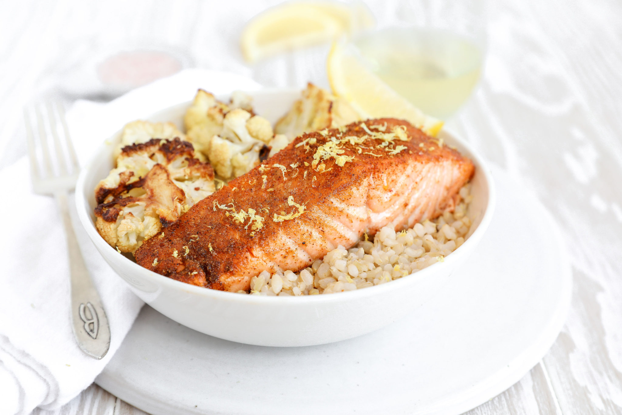 Spiced Baked Salmon via JennySheaRawn.com A side shot of a baked salmon filet in a bowl with rice and cauliflower.