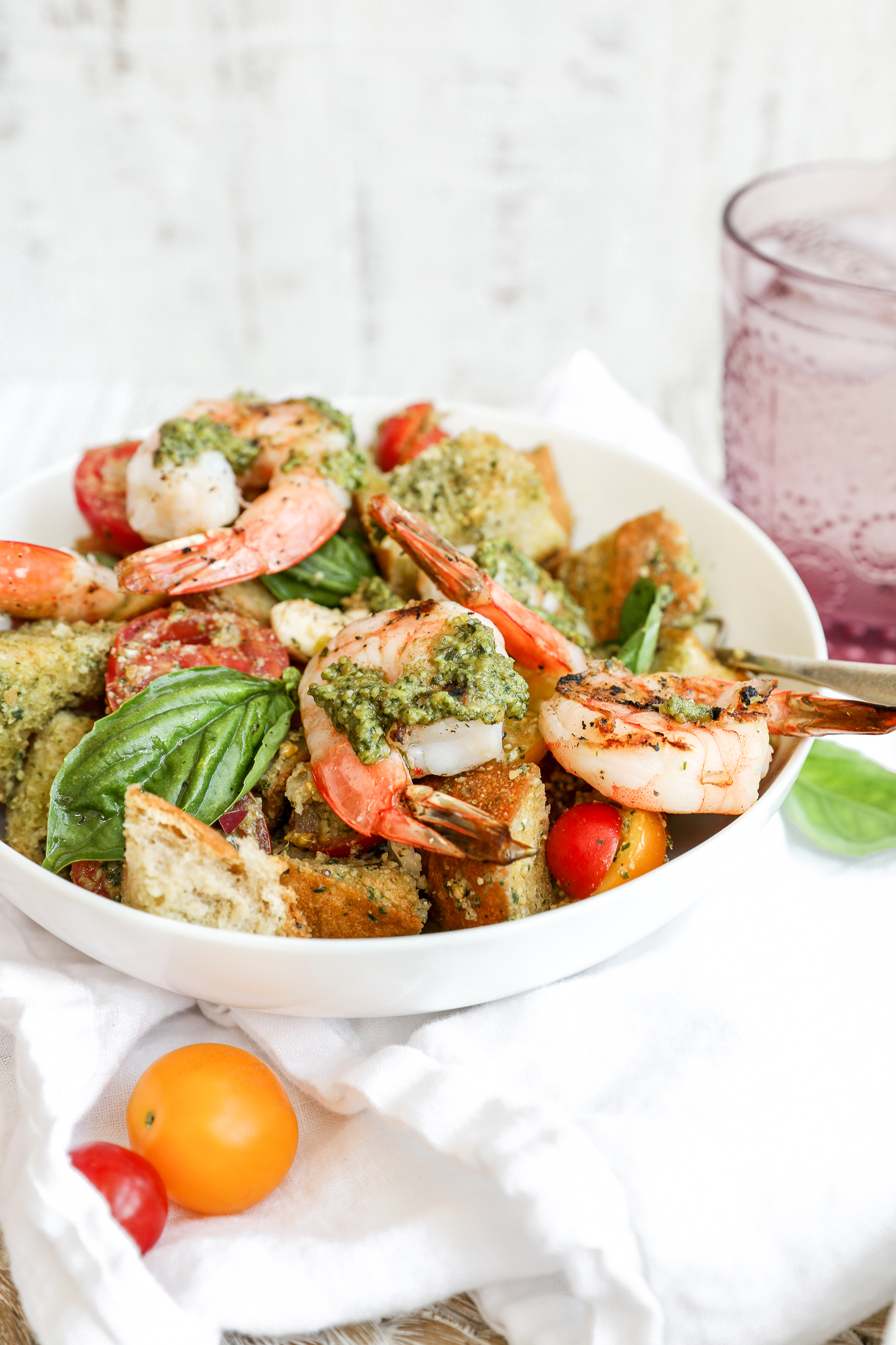 A white bowl of panzanella salad with shrimp and basil